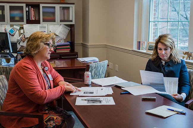 Nursing faculty members Gigi Smith and Joy Lauerer look at news reports they've gathered about workplace safety for nurses.